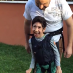 Un padre si inventa il modo per far giocare a calcio il figlio paralizzato: la reazione del ragazzo è emozionante